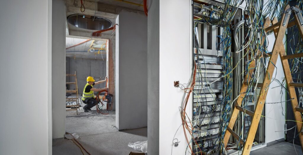 A person in a helmet working in a room with wires