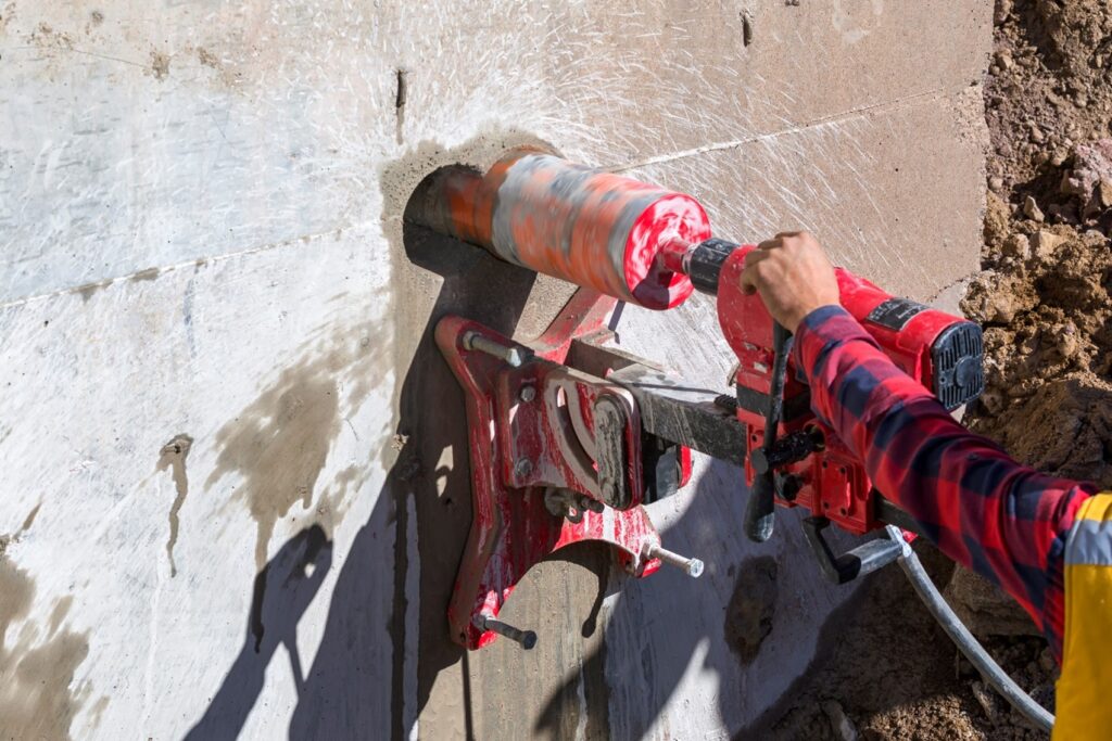 A person using a drill to cut through concrete