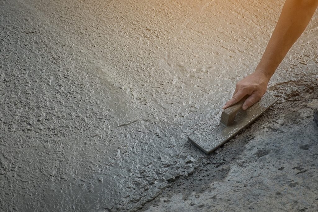 A person using a trowel to smooth concrete